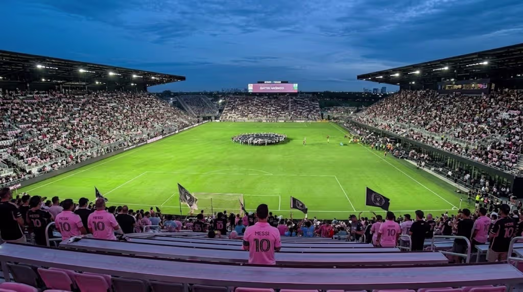 Panoramic view of a full soccer stadium at night with vibrant crowd and illuminated field