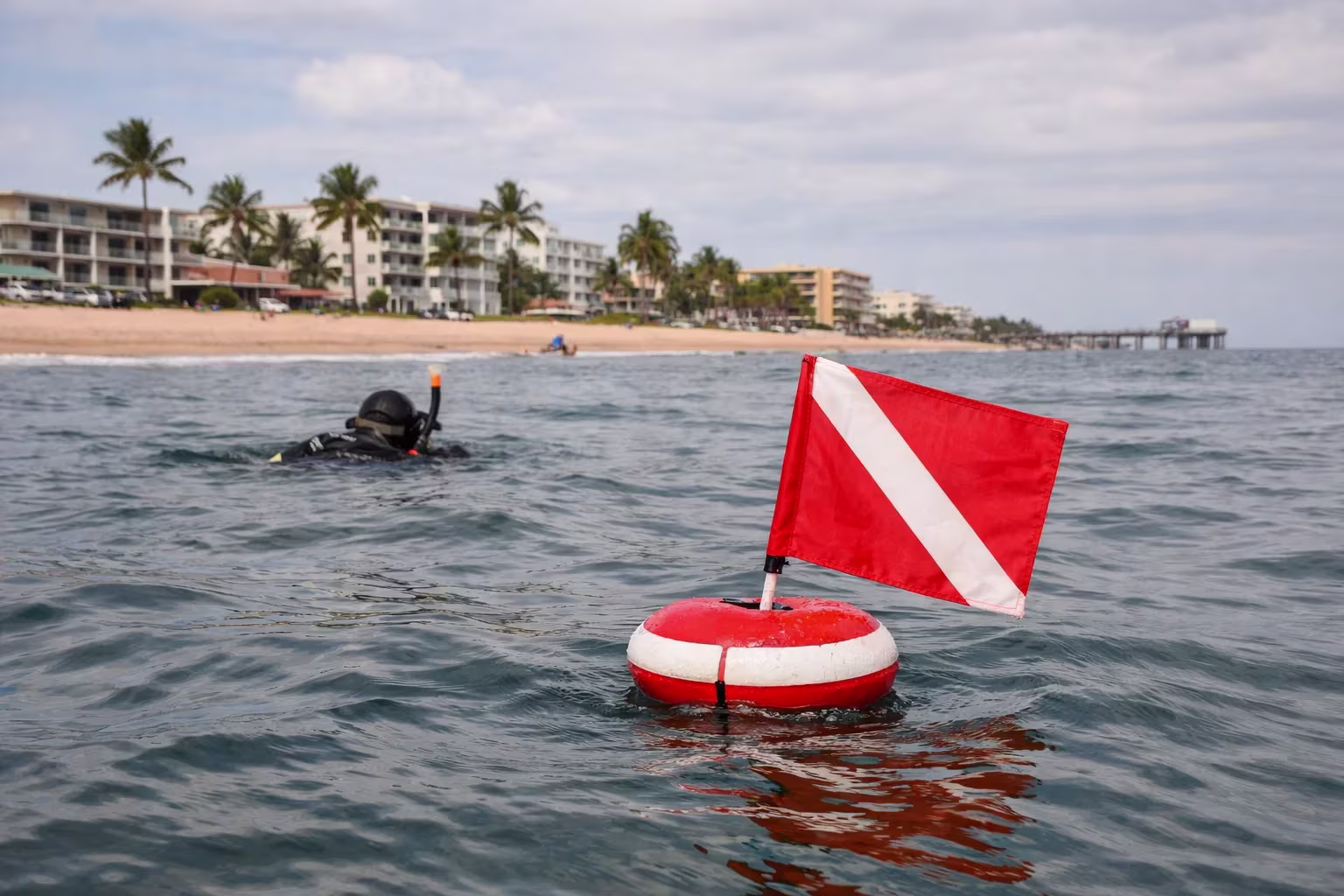 Red diver-down flag floating near a shore diver in Lauderdale-by-the-Sea Florida